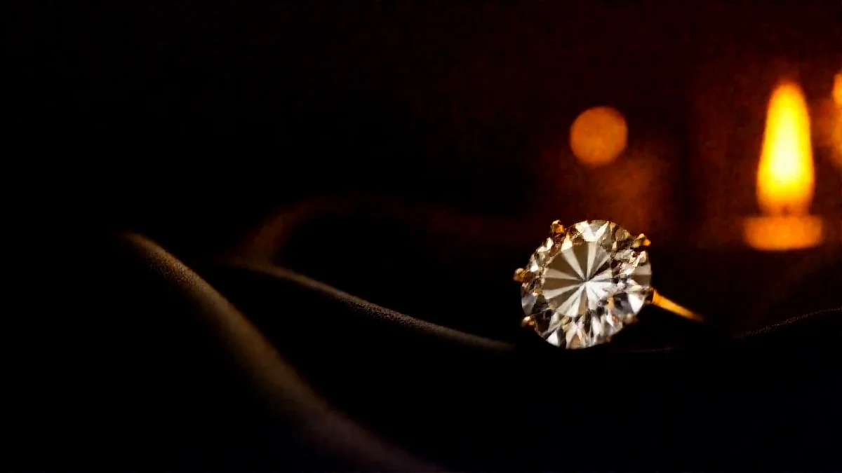 A diamond ring in warm candlelight on black silk